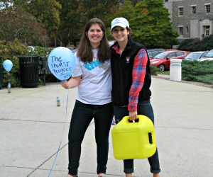 Two students holding containers of water as part of the Thirst Project.